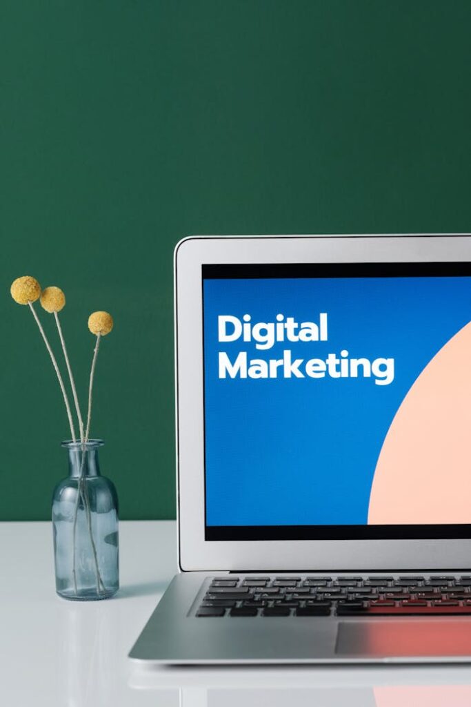 pexels-photo-6483583 A laptop displaying 'Digital Marketing' with a minimalist floral decor in a glass vase.